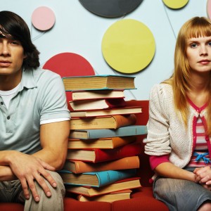 Young Couple Sitting with a Pile of Books --- Image by © Royalty-Free/Corbis