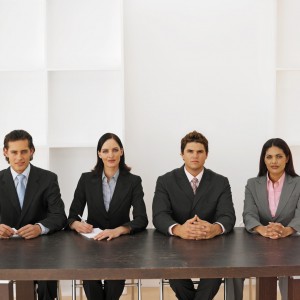 Front view portrait of four business executives sitting in a line --- Image by © Royalty-Free/Corbis